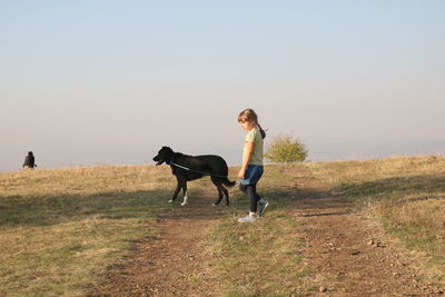 Little girl walking with her black dog outside on sunset