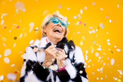 Smiling senior woman gesturing against colored background