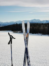 Wooden posts on snowcapped mountain by lake against sky