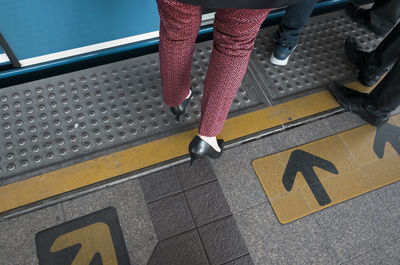 Low section of woman entering train at subway station