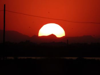 Silhouette landscape against orange sky