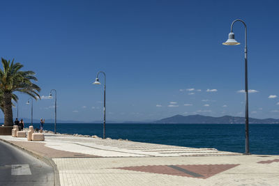 Street by sea against blue sky