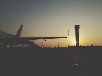 Silhouette of airplane against sky during sunset