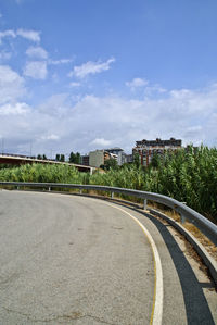 Road amidst buildings against blue sky