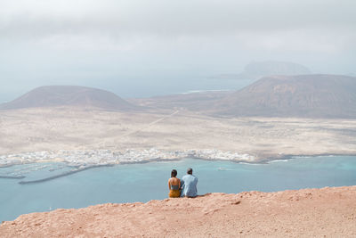 Couple relaxing on top of cliff in mirador del rio, lanzarote.