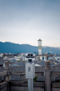 Close-up of coin-operated binoculars against buildings