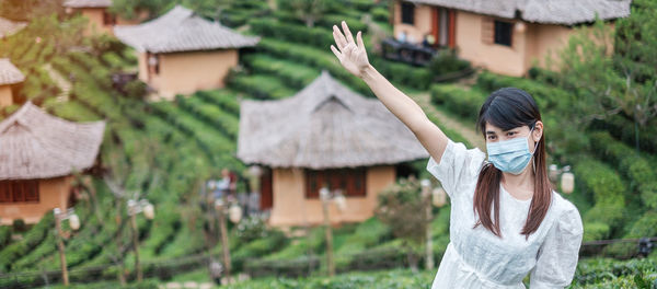 Woman with umbrella against plants outside building