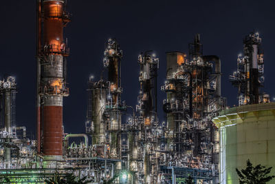 Illuminated factory against sky at night