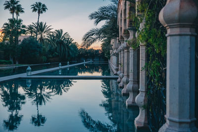 Reflection of trees and swimming pool in lake against sky