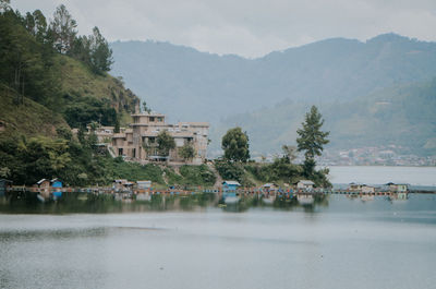 Scenic view of lake by buildings against sky