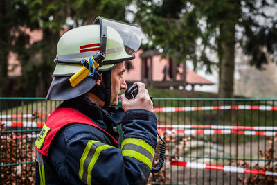 Side view of firefighter standing by fence