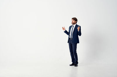 Full length of young man standing against white background