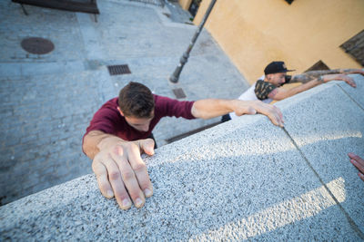 High angle view of male friends climbing wall