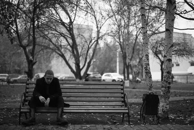 Full length of young man sitting on bench at park