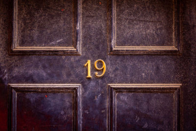 House number 19 on a dark wooden front door in london 