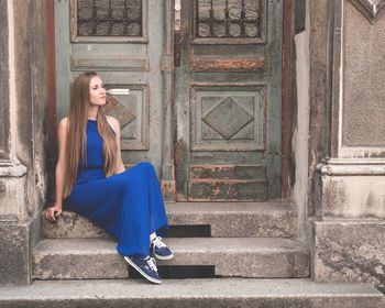 Full length of woman sitting in doorway