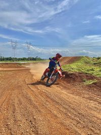 Motocross practice on sunday, riding bicycle on field against sky