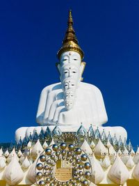 Low angle view of statue against building against clear blue sky