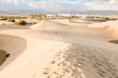 Scenic view of sand dunes at beach against sky