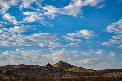 Desert peaks in early morning light with blue sky and clouds above