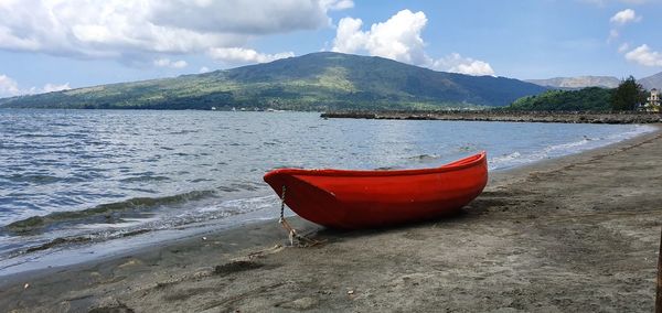 Boat moored on beach against sky