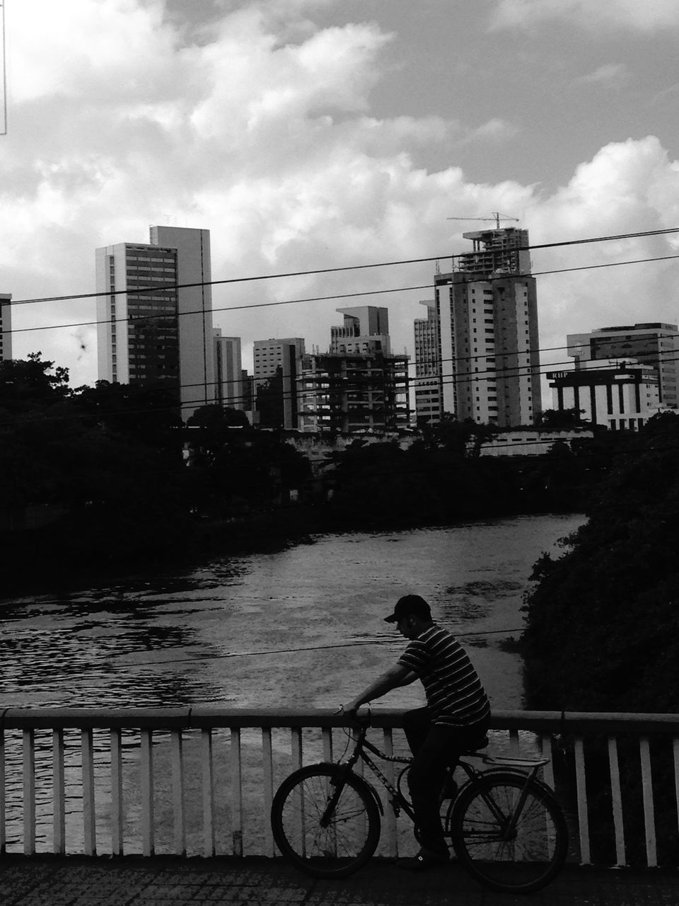 building exterior, architecture, built structure, city, bicycle, lifestyles, sky, water, men, full length, leisure activity, railing, city life, river, transportation, cityscape, side view, street