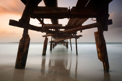 Pier on sea against sky at sunset