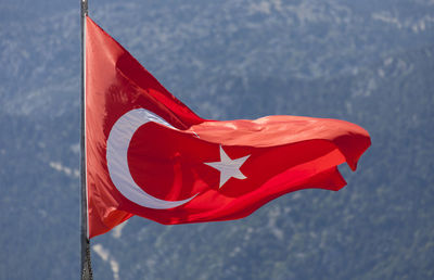 Close-up of red flag waving against mountains