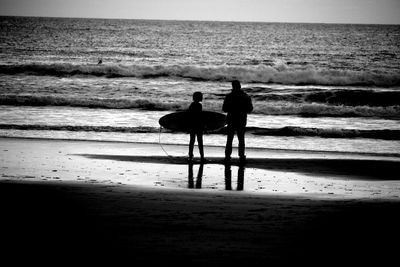 Silhouette of people on beach at sunset