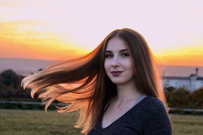 Portrait of beautiful young woman against sunset sky