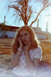 Portrait of young woman against bare tree