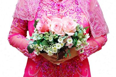 Midsection of woman with bouquet during wedding anniversary against white background