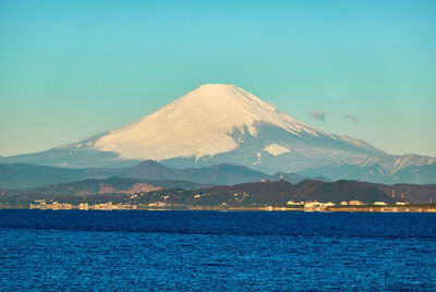 Scenic view of sea and snowcapped mountain against clear sky