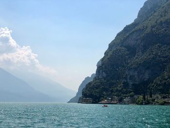 Scenic view of sea by mountains against sky