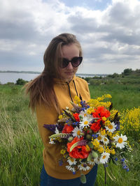 Young woman wearing sunglasses on field against sky