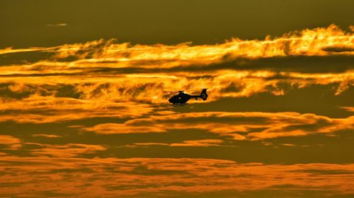 Silhouette flying in sky