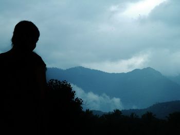 Rear view of silhouette man against mountains against sky