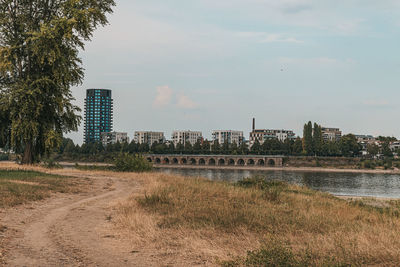 Buildings by river against sky