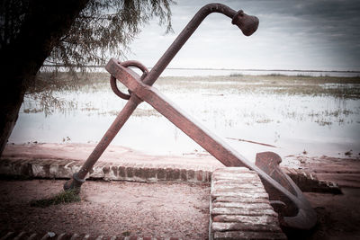 Close-up of rusty metal on beach against sky