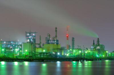 Illuminated factory against sky at night