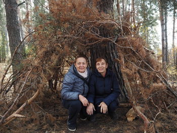 Walking elderly people in the autumn forest. imitation of a hut made of look at the camera 