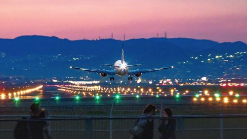 People at airport runway against sky at night