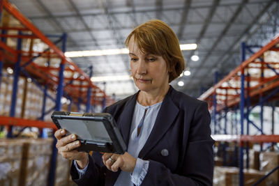 Mature manager using tablet pc at warehouse