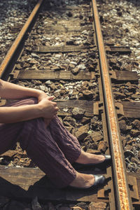 Low section of person sitting on railroad track