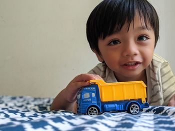 Portrait of cute boy with toy on bed at home