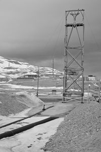 Road by snow covered land against sky