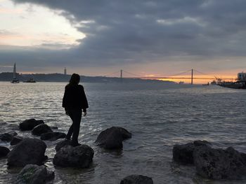 Rear view of man looking at sea against sky