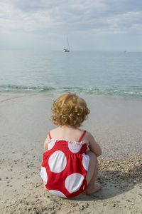 Rear view of girl crouching on beach