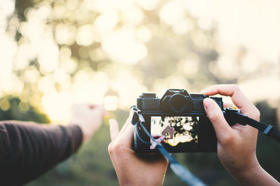 Close-up of hands photographing with camera outdoors