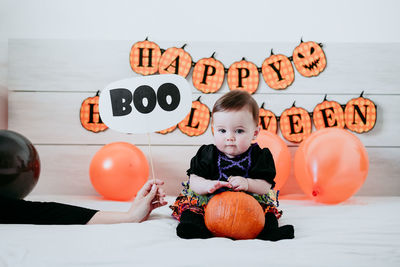 Portrait of cute girl with pumpkin sitting on bed at home